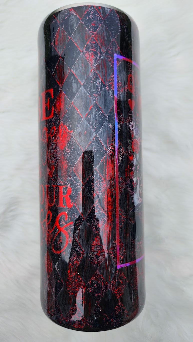 "Glossy tumbler with a dark gothic design featuring a queen-like woman with black wavy hair, blue eyes, and a jeweled crown with a red heart. She wears a black corset and lace sleeves, holding a large red heart in her hands. The background includes roses, playing card suits, and a red-and-black diamond harlequin pattern."
